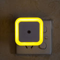 Neon light switch cover with yellow border on a wall switch.