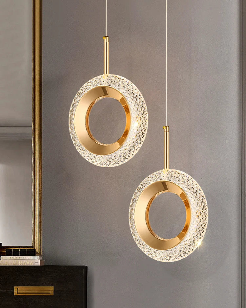 Two gold pendant lights hanging against a gray wall.