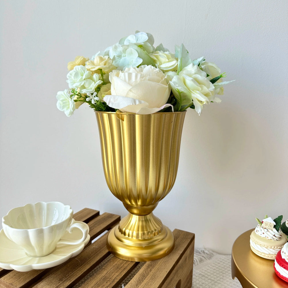 Gold urn with white flowers on a wooden surface with a white background