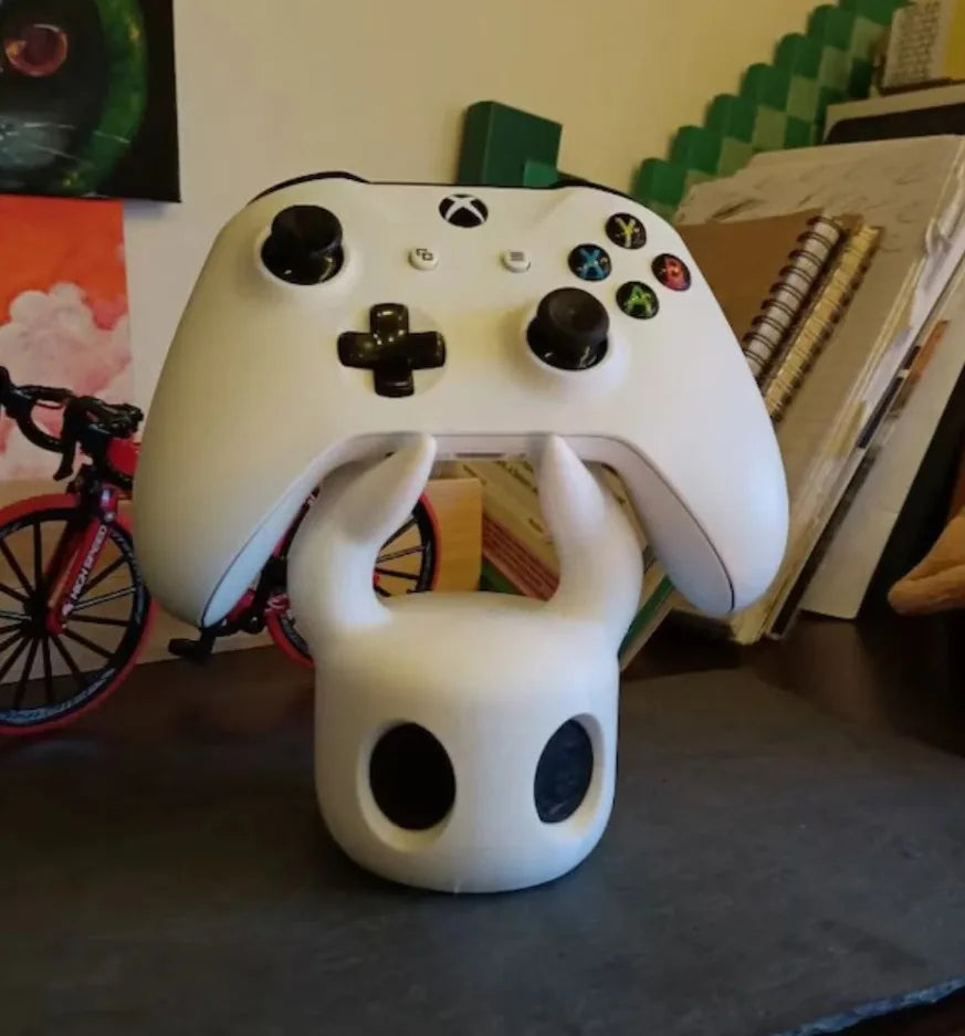 White gaming controller with a small white creature figure on a surface