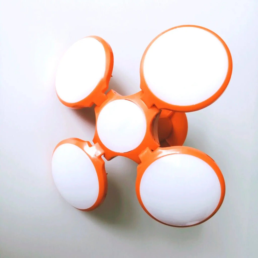 An orange and white four-light wall fixture with a central mounting hub, photographed against a plain light background.