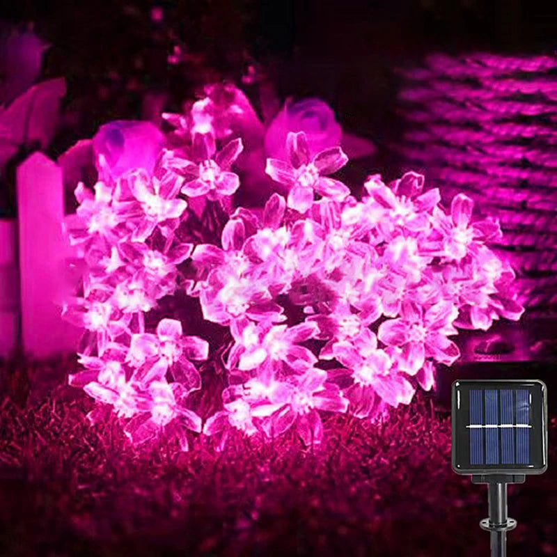 String of pink flower-shaped lights with solar panel on grass