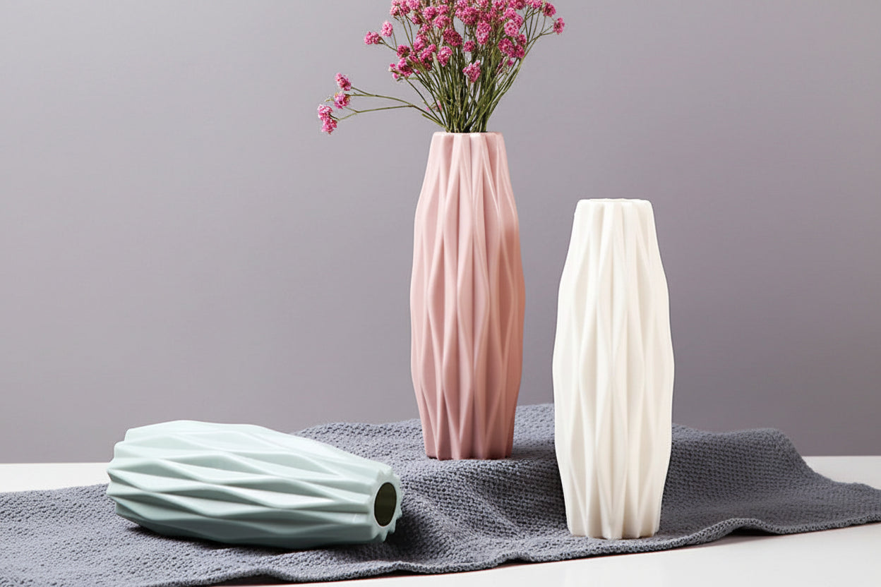 Three decorative vases with wavy texture on a gray surface, one pink and two white.