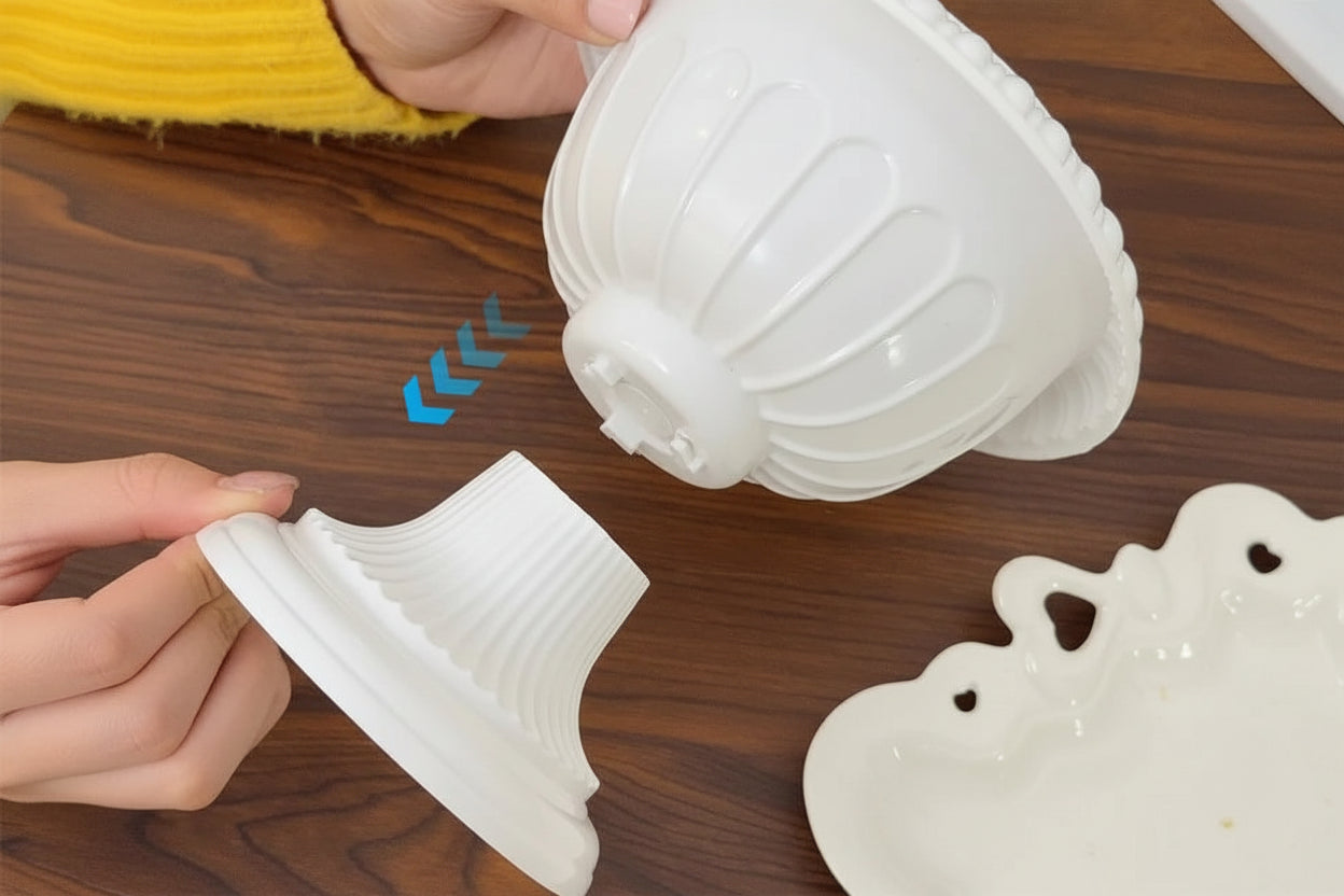 A person's hands are shown assembling a white plastic decorative bowl or vase mold on a wooden table. The product is shown in disassembled parts with blue arrow graphics and the text 'simple and quick assembly design'.