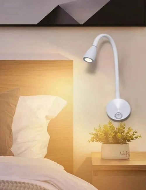 Bedroom scene with a flexible arm wall light on a nightstand next to a bed.