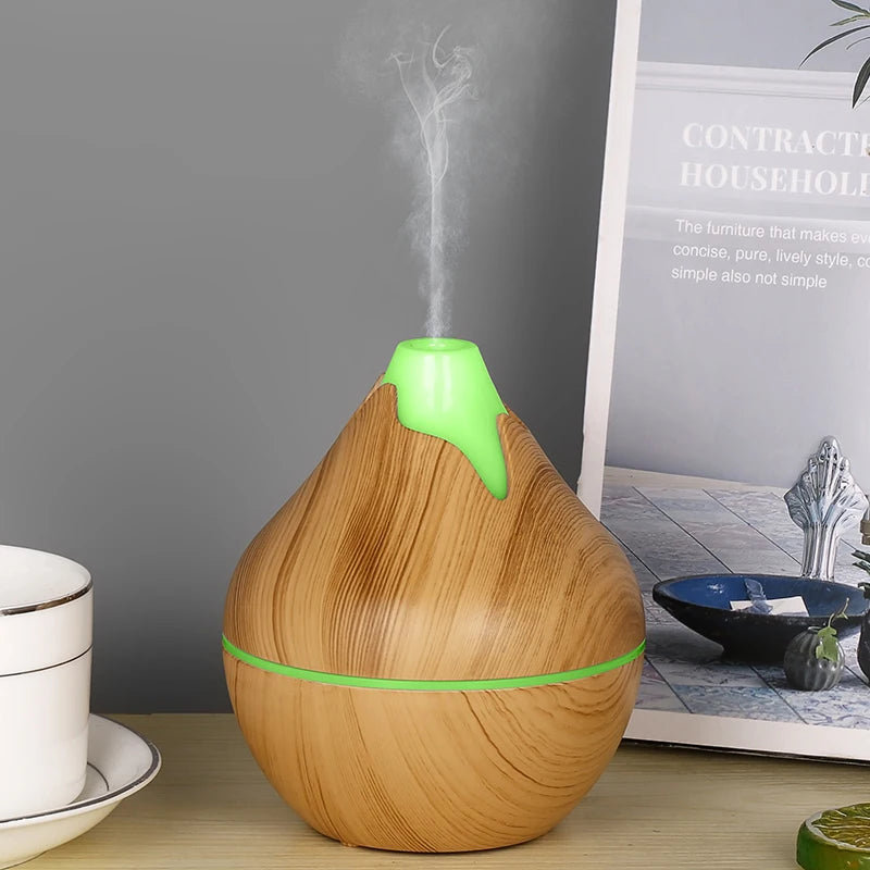 Wooden essential oil diffuser with green accents on a table