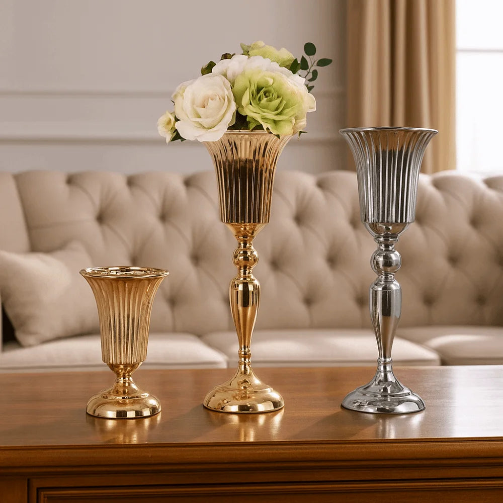 Three decorative vases on a wooden surface with a floral arrangement in the center.