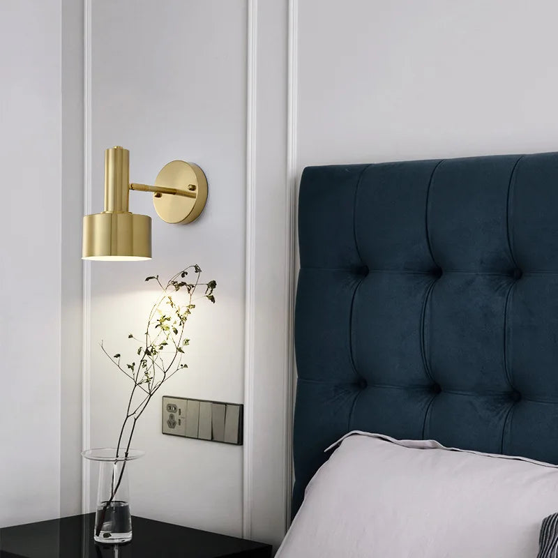 Modern bedroom with a gold wall sconce, dark blue tufted headboard, and white bedding.