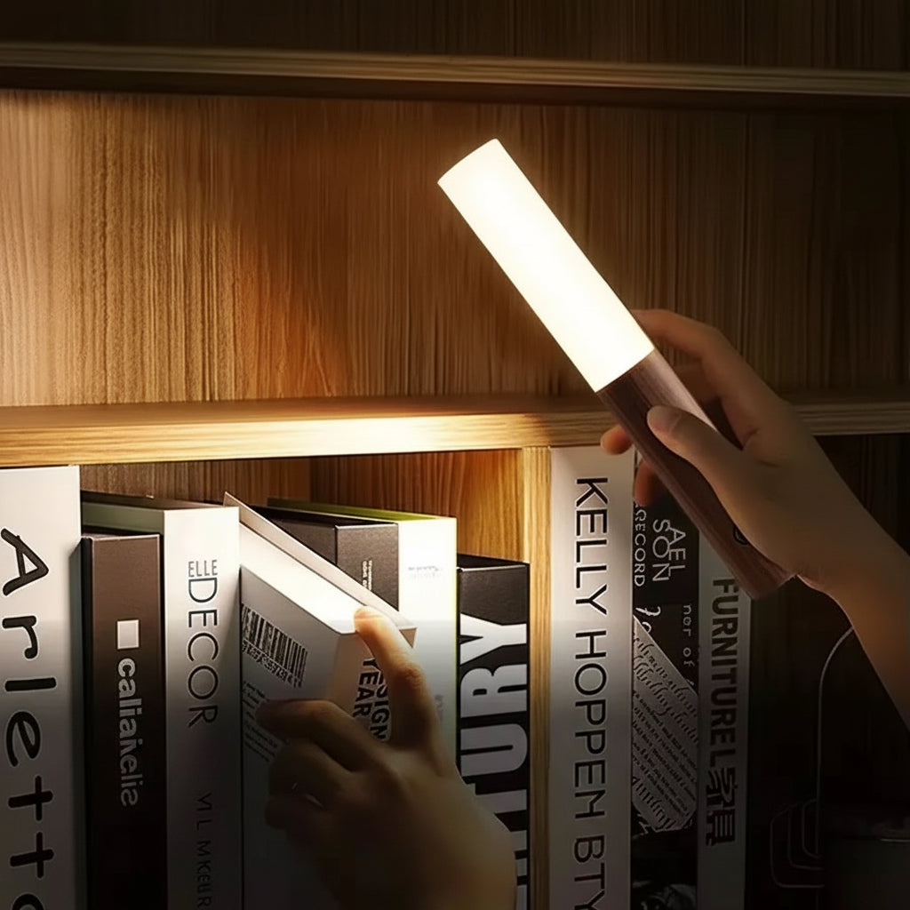 Hand holding a small light source over books with text about its features.