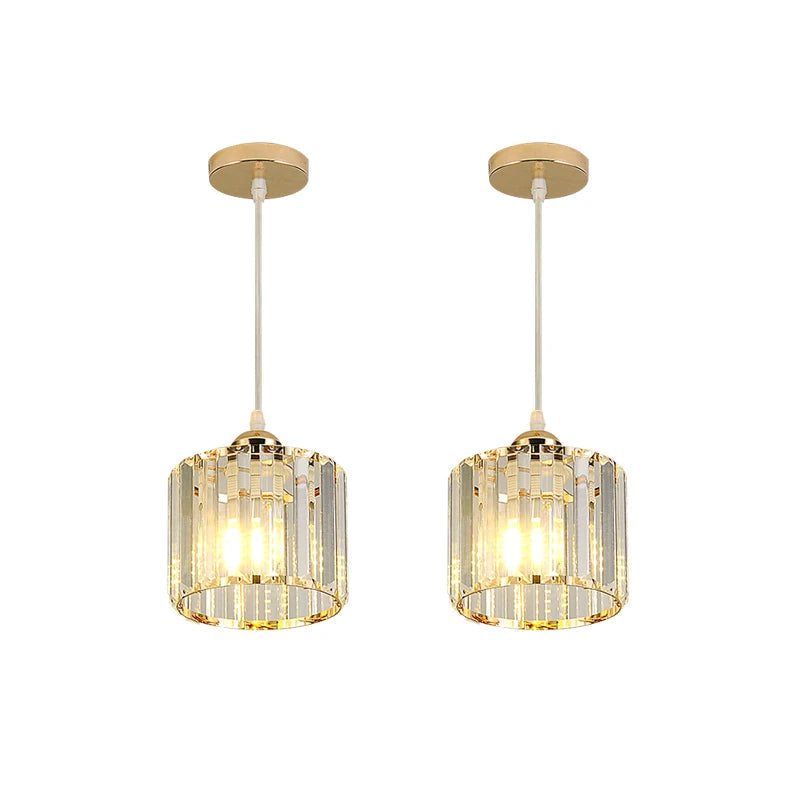 Two matching modern pendant lights with gold-toned metal fixtures and clear cylindrical crystal-like shades