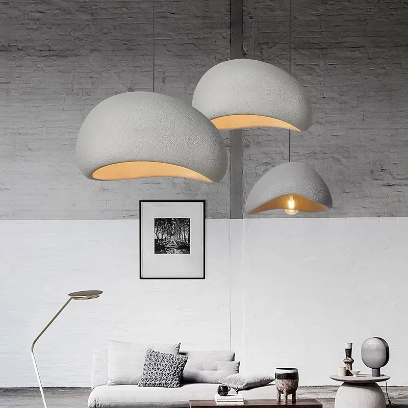 Modern living room with pendant lights, sofa, and decorative items against a gray brick wall.