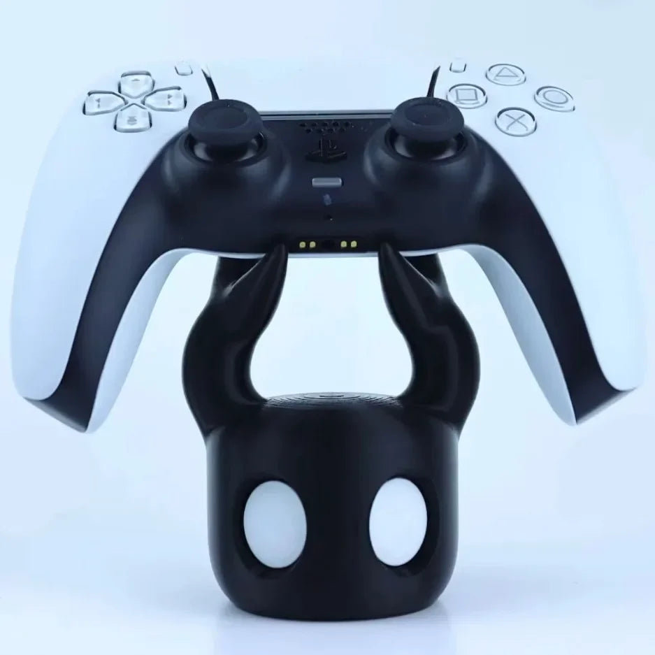 Black gaming controller on a black stand with a white background