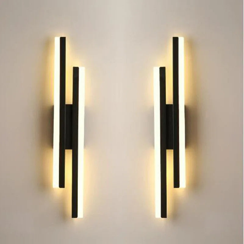 Two modern black wall sconces on a light gray wall.