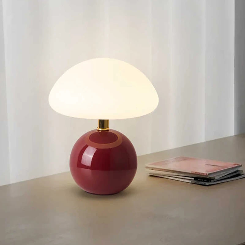 Table lamp with a red base and white shade on a surface with a light background