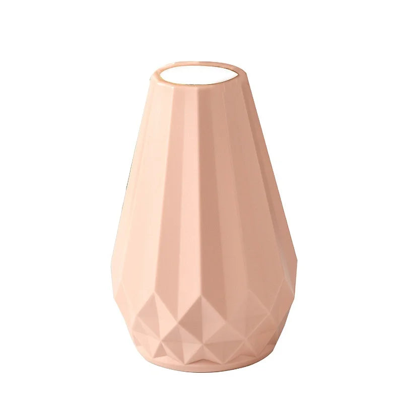 A faceted geometric ceramic vase in a soft blush pink color, shown against a plain white background.