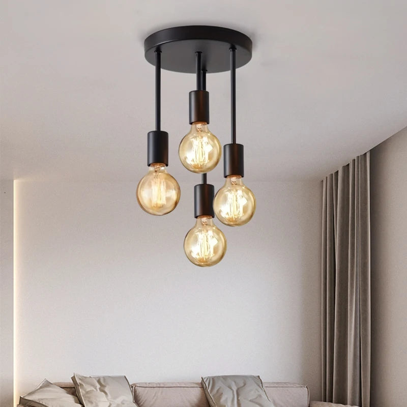 Modern ceiling light fixture with four exposed bulbs in a living room setting.