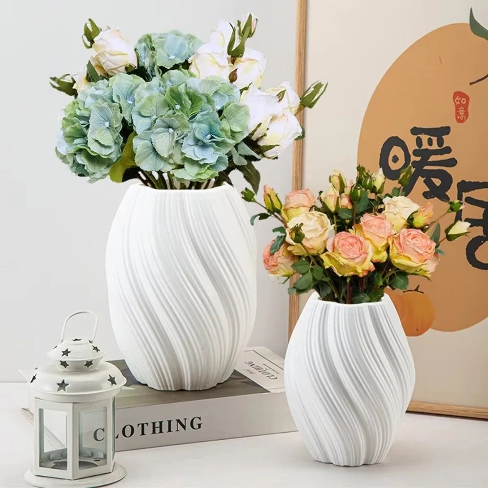 Two white marble-patterned vases with floral arrangements on a surface.