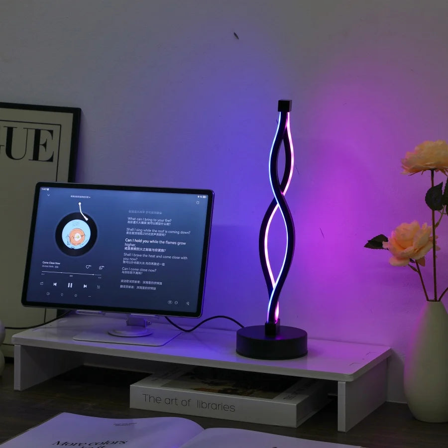 Neon lamp on a desk with a computer monitor and flowers in the background
