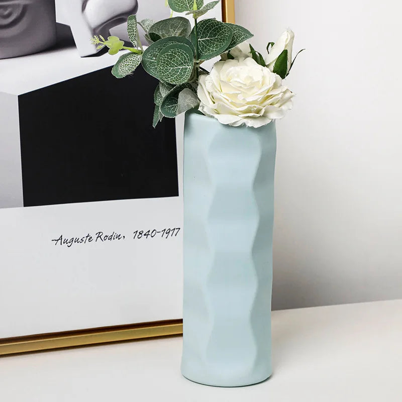 Light blue ceramic vase with flowers on a white surface