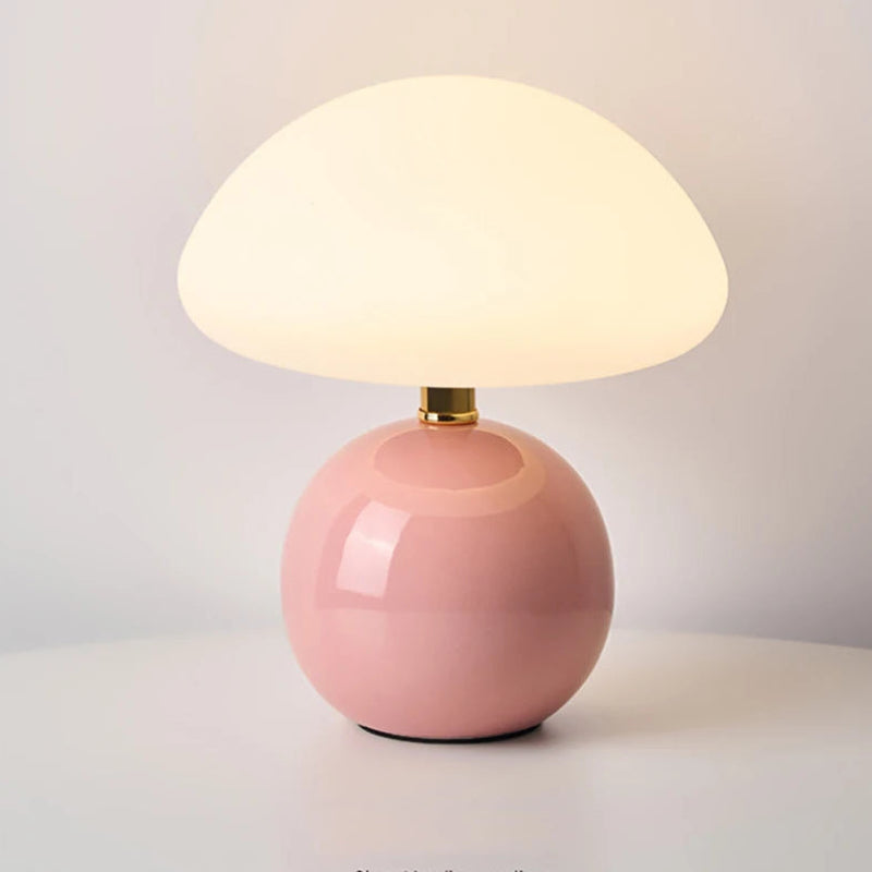 Pink table lamp with a white glass shade on a light background