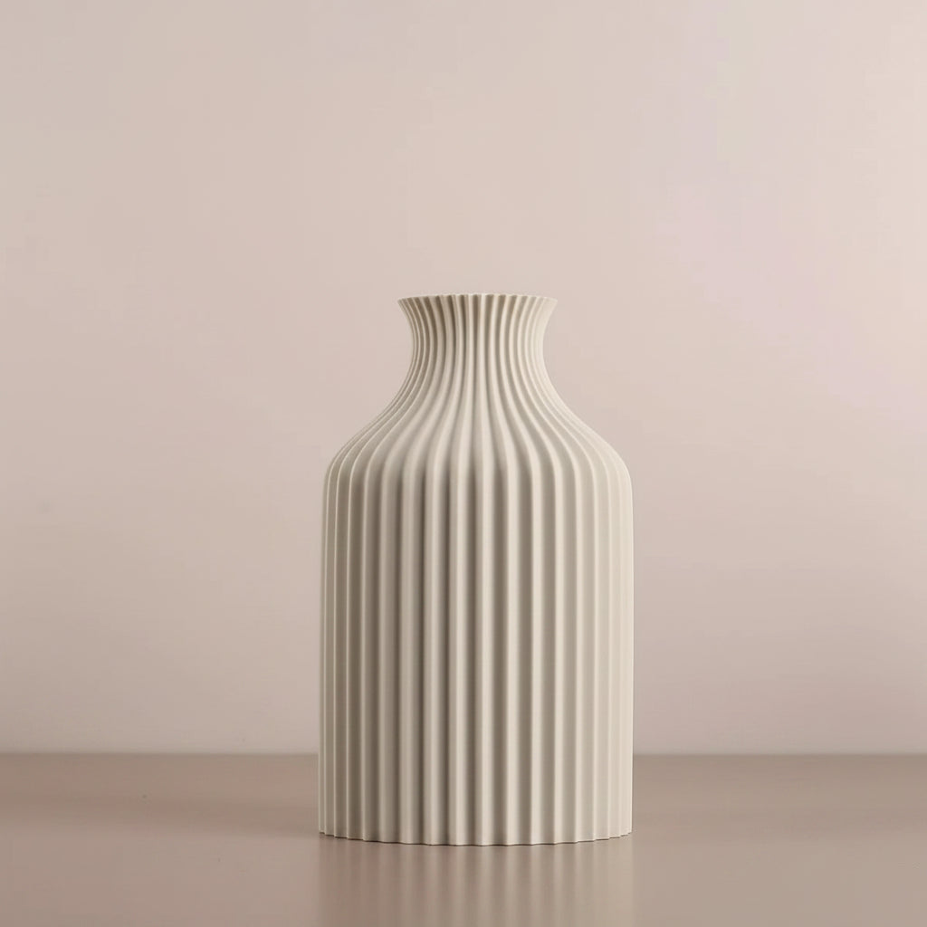 A ribbed ceramic vase in off-white, shown on a tabletop with decorative props 