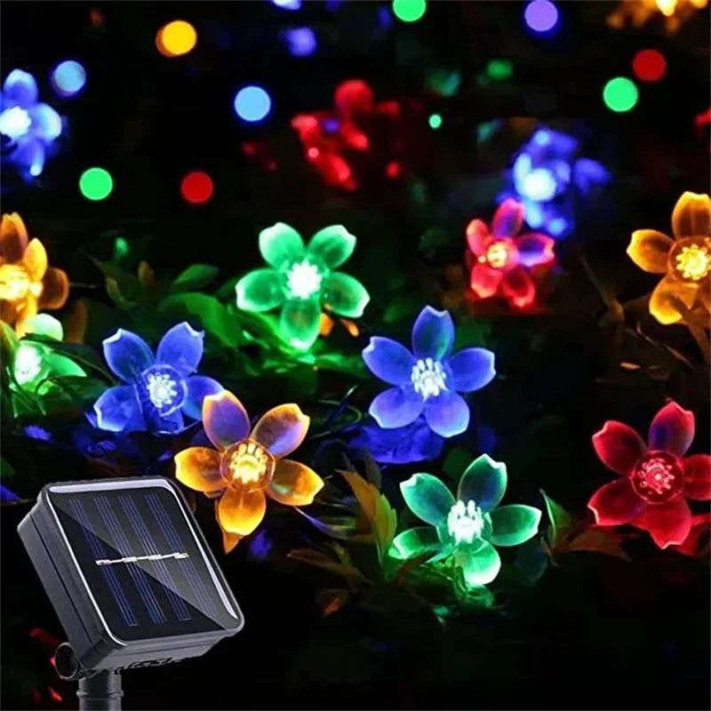 Colorful flower-shaped string lights with a solar panel on a dark background