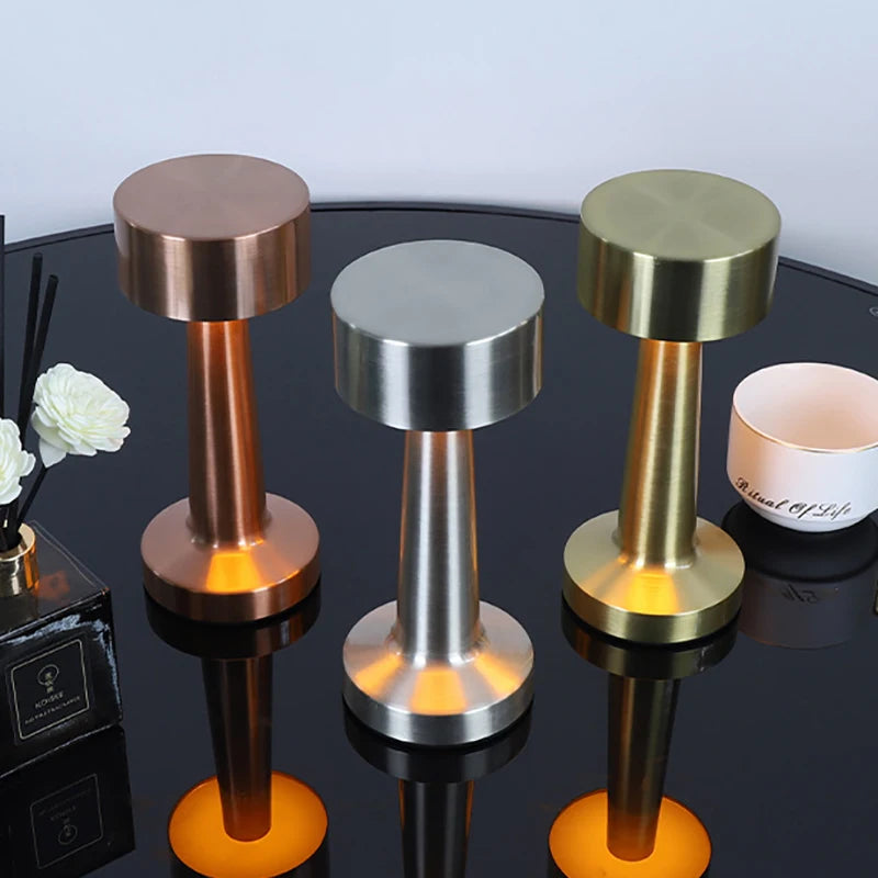 Three metallic door stops in bronze, silver, and gold on a reflective surface.