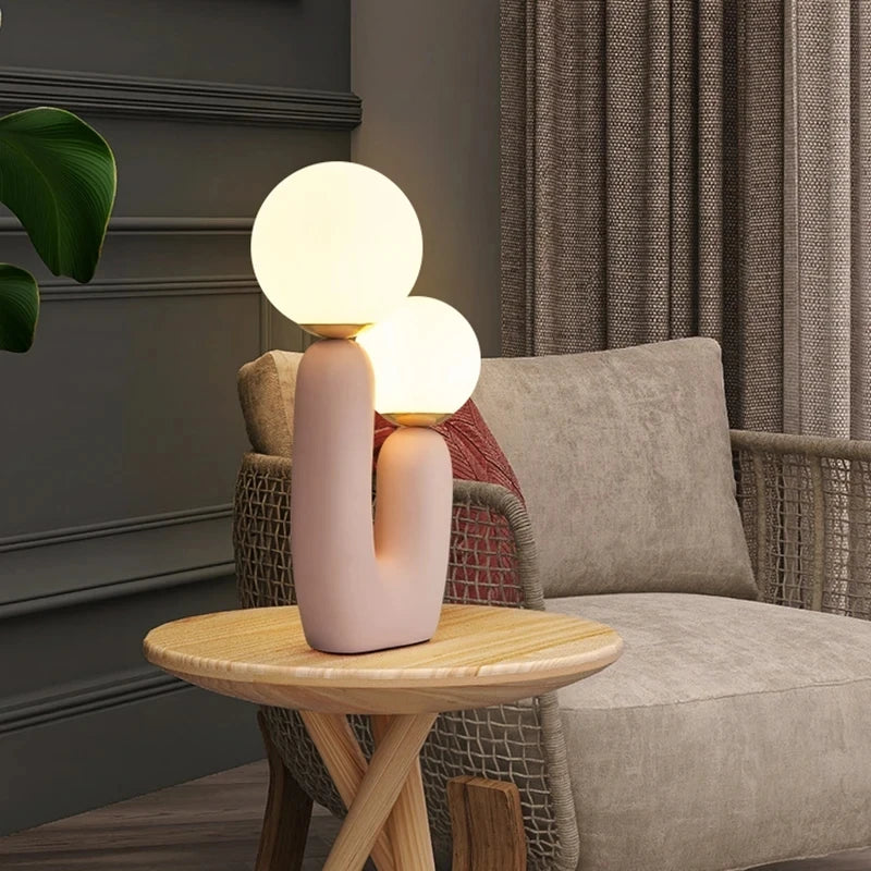 Modern table lamp with spherical bulbs on a wooden side table in a living room setting.