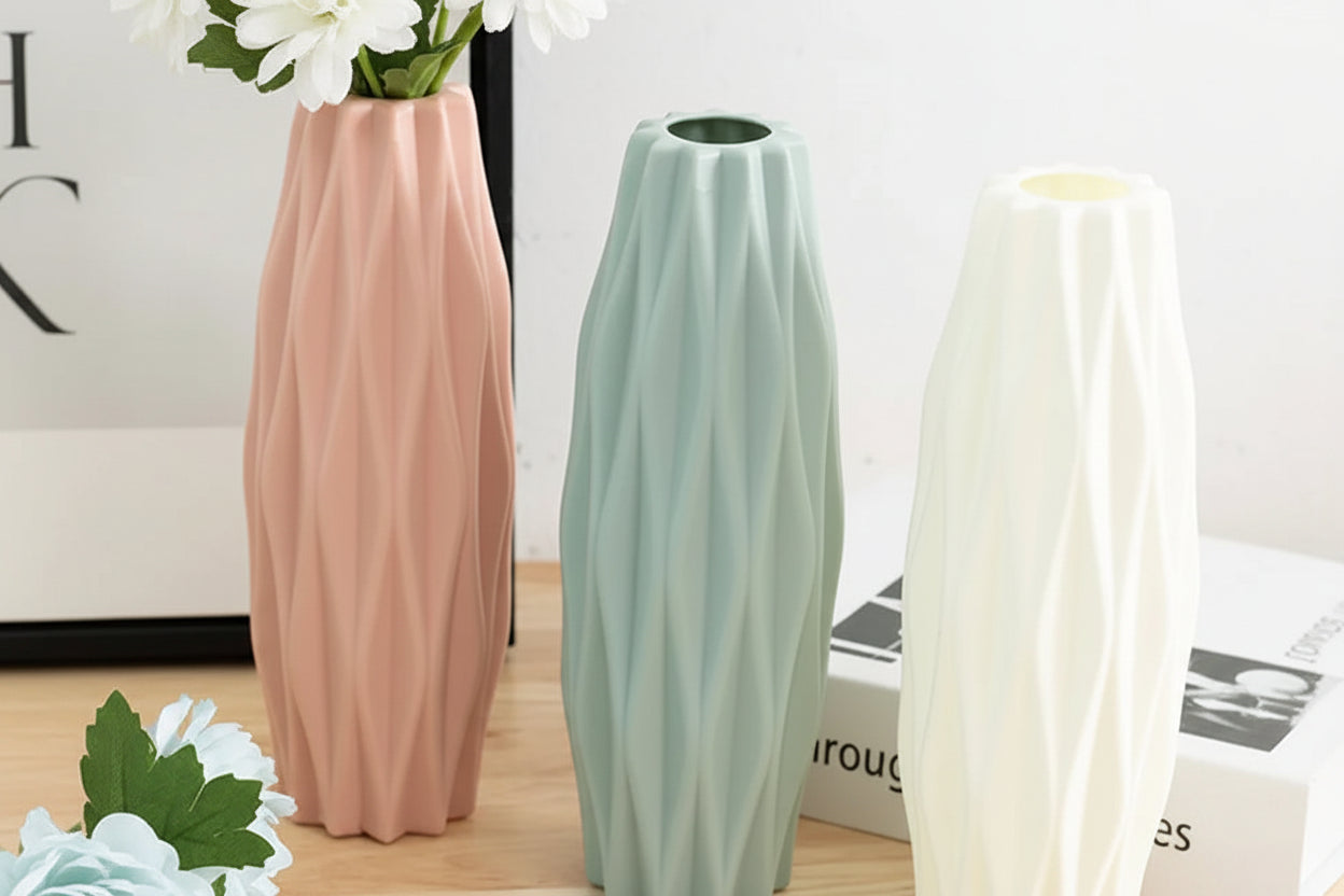 Three decorative vases in pink, green, and white on a wooden floor.