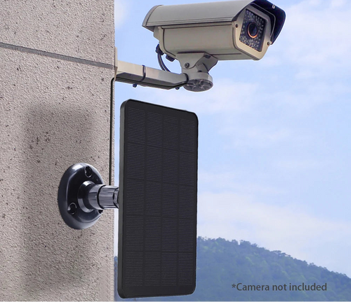 Solar panel attached to a wall with a camera on top, against a blue sky.