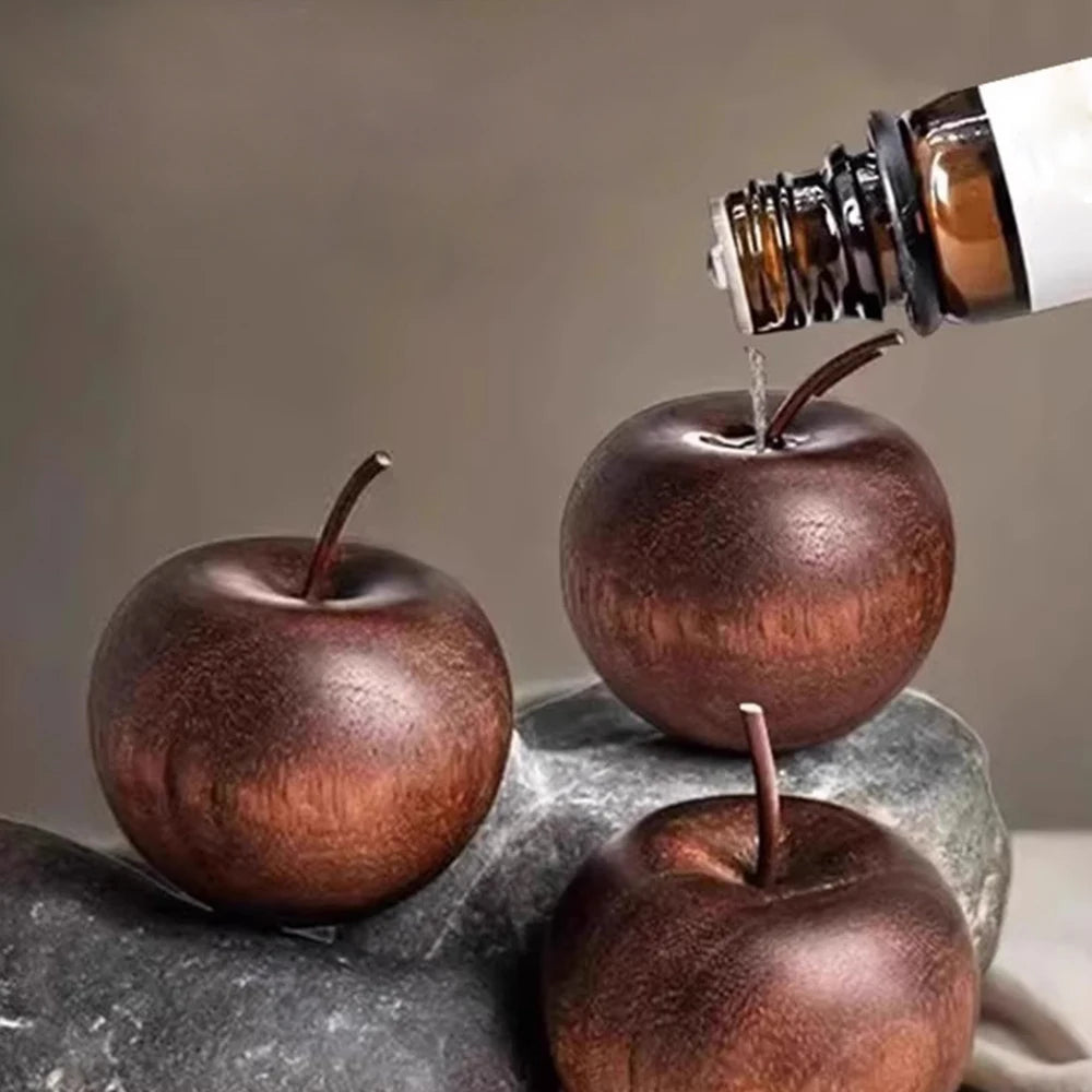Wooden apples being filled with a liquid from a bottle on a gray surface.