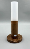 Tall cylindrical light fixture with wooden base on a gray background