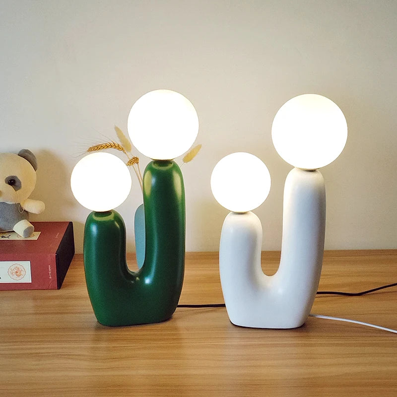 Two unique table lamps with spherical lights on a wooden surface.