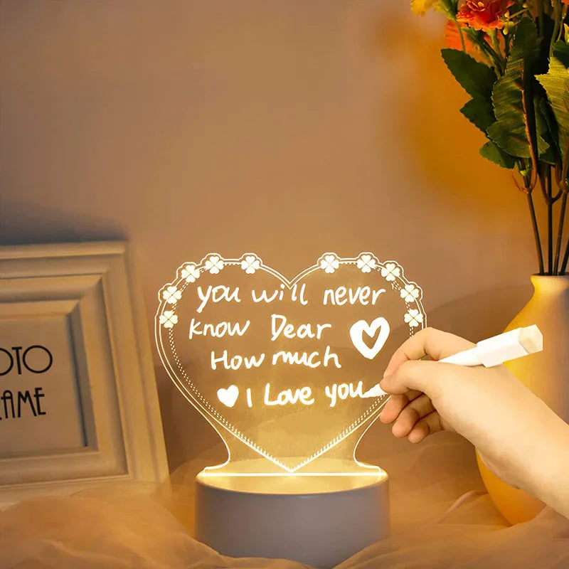 Heart-shaped night light with romantic message, held by a hand, in a warm indoor setting.