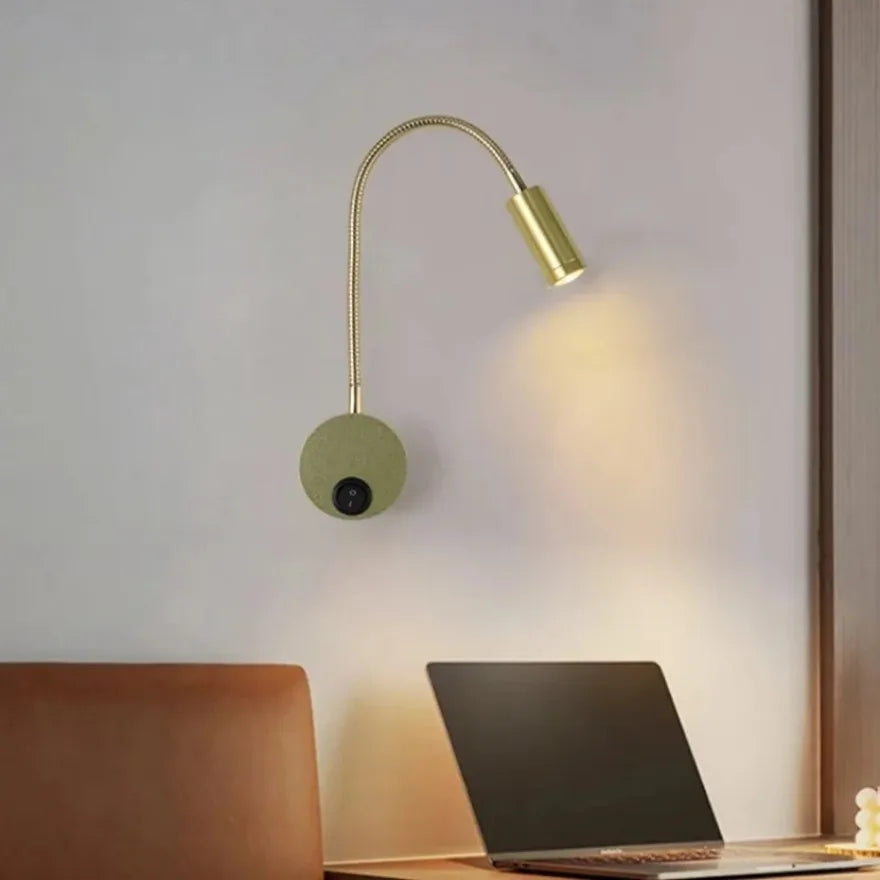 Gold wall-mounted lamp illuminating a desk with laptops.