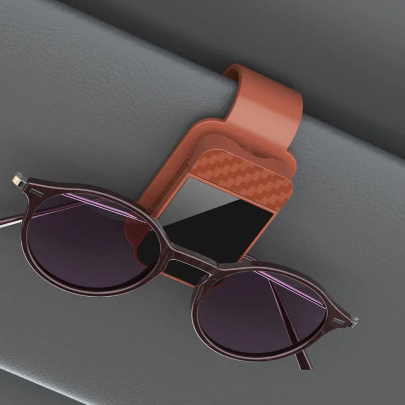 Sunglasses on a car visor with a brown sunglasses holder.