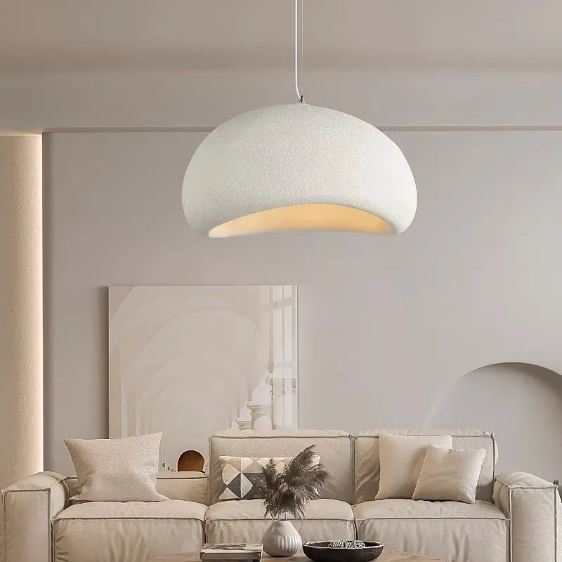 Modern pendant light hanging above a beige sofa in a living room.