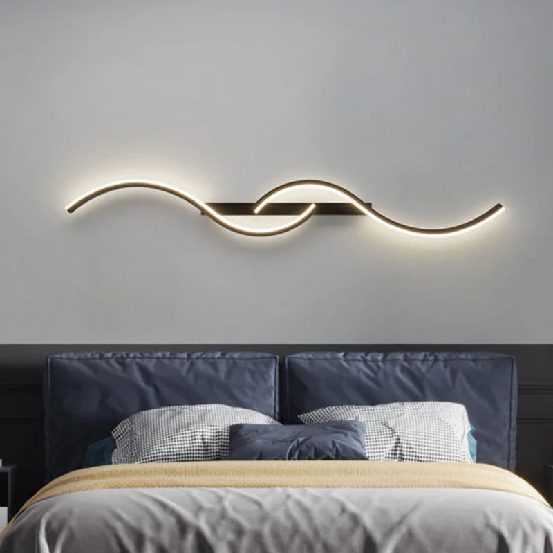 Modern wall light fixture above a bed with dark headboard and pillows.