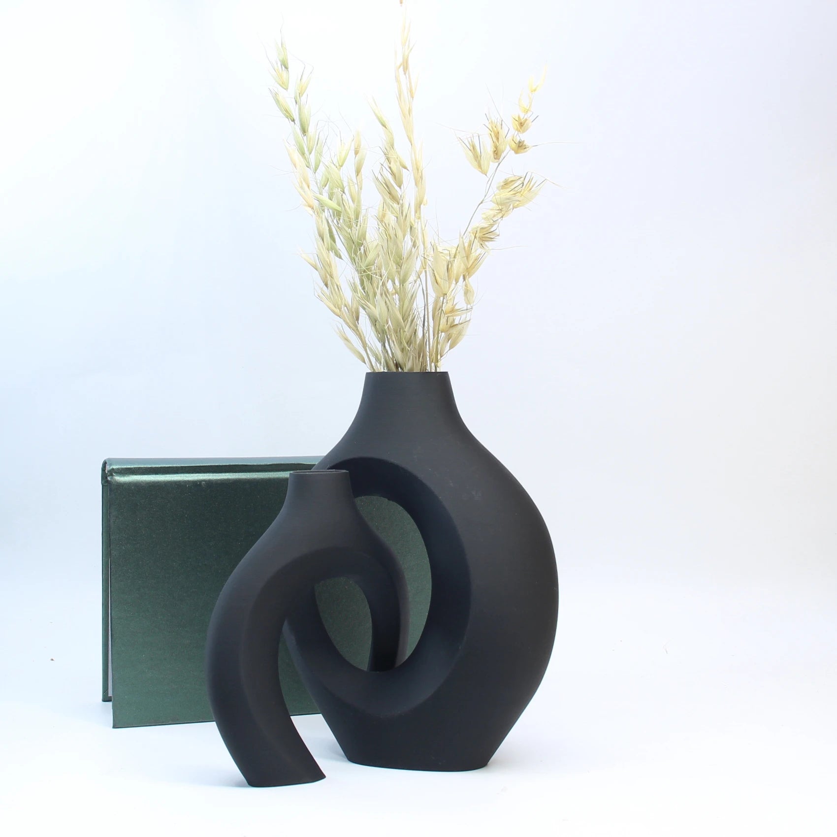 Black decorative vase with dried plants on a white background