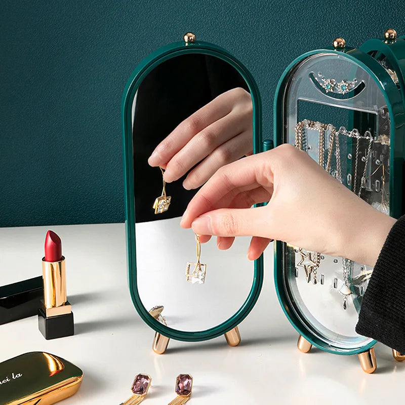 Person trying on earrings in front of a compact mirror with jewelry and lipstick visible.