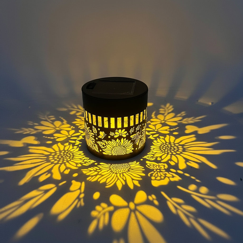 A small cylindrical black solar lamp with a floral cutout pattern, shown casting a yellow flower shadow on a wall. White text overlays indicate the product's dimensions as 8.