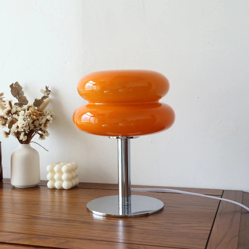 Orange lamp with a white vase and decorative object on a wooden surface.