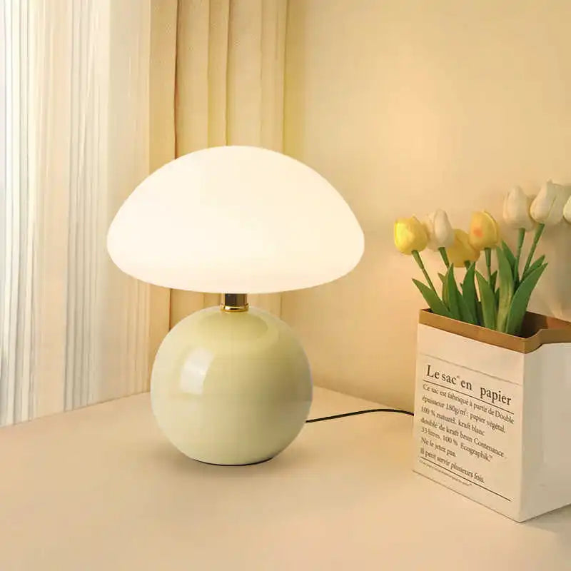 White table lamp on a desk with a small plant in the background