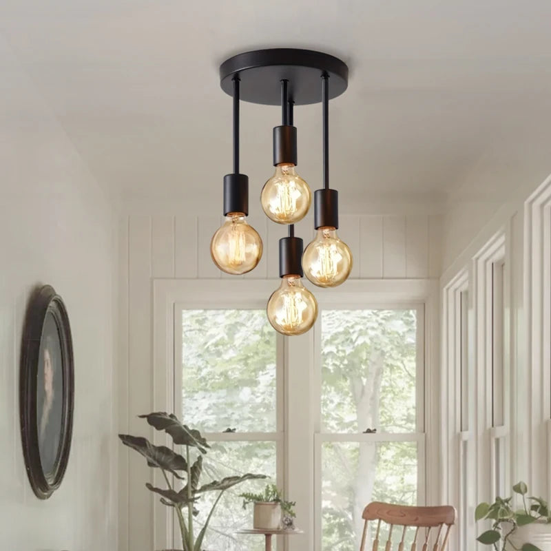 Ceiling light fixture with three exposed bulbs in a room with a window and plants.