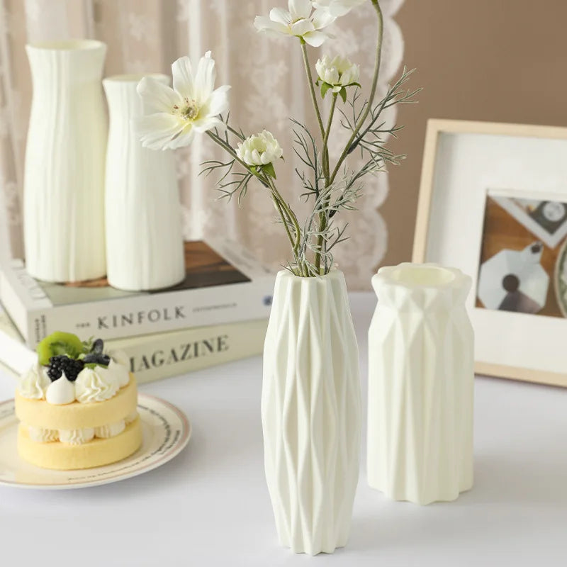 White ceramic vases with a small cake and books on a table