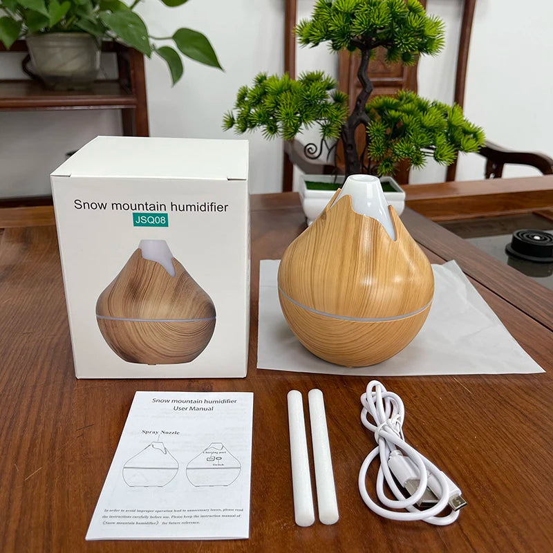 Wooden humidifier with packaging, user manual, and accessories on a wooden table.