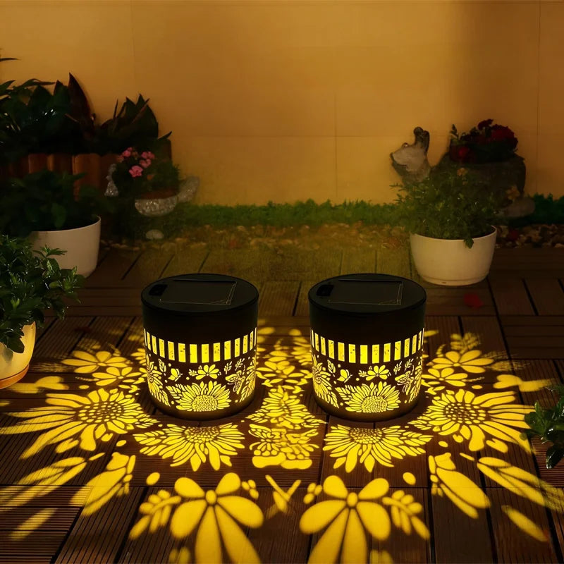 Two solar-powered outdoor lights with floral patterns casting shadows on a wooden surface.