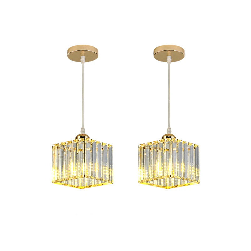 Two matching hanging pendant lights with gold-toned circular ceiling mounts, white cords, and clear rectangular crystal-like shades that glow warm yellow.