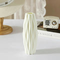 White textured vase with dimensions on a table with a hat and vintage radio in the background