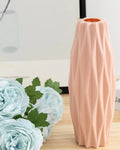 Pink textured vase with floral arrangement on a wooden surface